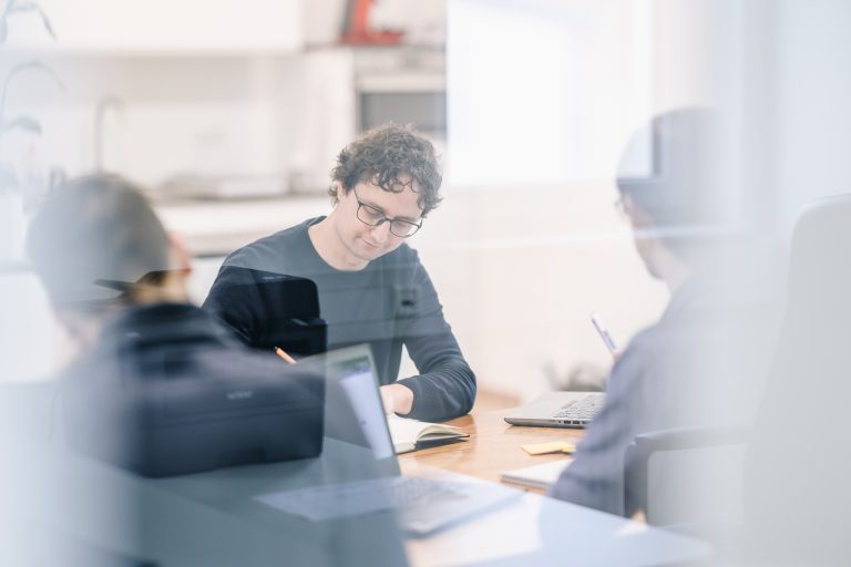 Drei Entwickler arbeiten gemeinsam am Tisch